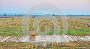 Sunset over farm field with hay bales in summer