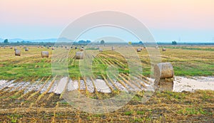 Sunset over farm field with hay bales