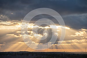 Sunset over the forest with sun rays breaking through clouds