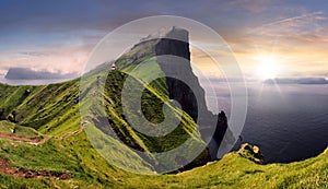 Sunset over green mountain with atlantic ocean, Faroe islands - Kallur lighthouse