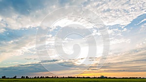 Sunset over a green wheat field and a metallurgical plant, timelapse