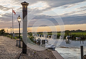 Sunset over the harbor of Ribe with the high water mark column in the front, Denmark