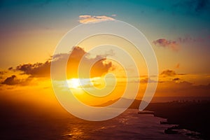 A sunset over the Hawaiian Island of Oahu as seen from a mountain top with the city of Waikiki Beach and Diamond Head in the