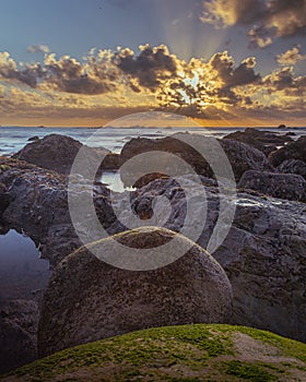 Sunset over the horizon of the ocean with a rocky shoreline in Sao Martinho do Porto, Portugal