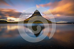 Sunset over Kirkjufell mountain with reflection in a nearby lake in Iceland