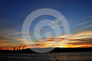 Sunset over the Kola Bay with a view of the cranes. Murmansk is located on the rocky eastern coast of the Kola Bay of