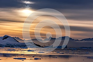 Sunset over the lagoon with drifting icebergs and snow mountains