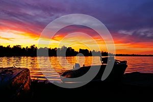 Sunset Over Lake With Fishing Boat Docked On Shore