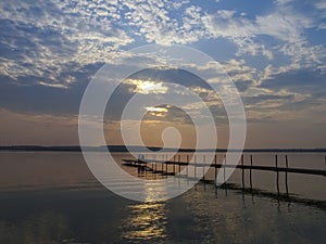 Sunset over the lake with a pier, warm summer evening.