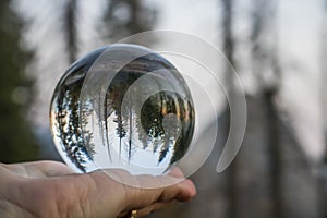 Sunset over Mountains with Forest and Moon Captured in Glass Ball Held in Palm