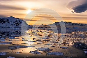 Sunset over the lagoon with drifting icebergs and snow mountains