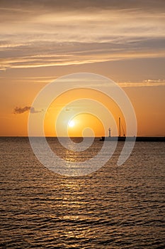 Sunset over Mykonos island, Cyclades, Greece. Lighthouse, orange yellow sky sparkle sea. Vertical