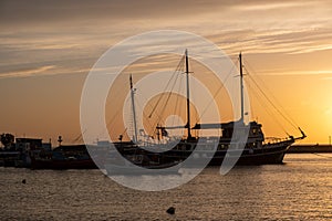 Sunset over Mykonos island, Cyclades, Greece. Moored ship at port, beacon orange sky sparkle sea