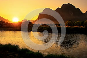 Sunset over Nam Song River with silhouetted rock formations in V