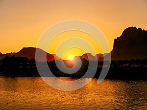 Sunset over Nam Song River with silhouetted rock formations in V