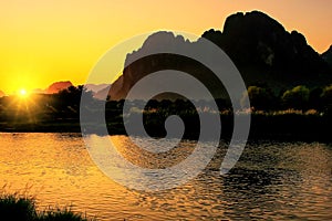 Sunset over Nam Song River with silhouetted rock formations in V