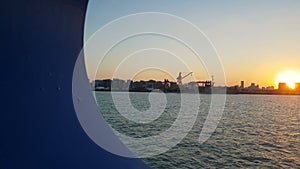 Sunset over the ocean and seaport. View of the sunset and the ocean through the porthole of the ship.View of the ocean and the cit