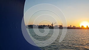 Sunset over the ocean and seaport. View of the sunset and the ocean through the porthole of the ship.View of the ocean and the cit