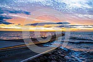 Sunset over ocean and small boat jetty in Melbourne.