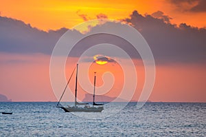 Sunset over ocean with small boat silhouette photo