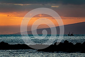 Sunset over the ocean with two fishing boats