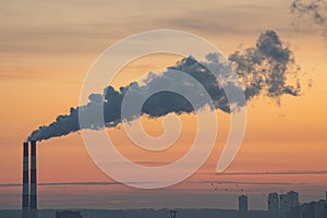Sunset over power plant with smokestacks, orange and blue sky, industrial structure contrasting soft light. m