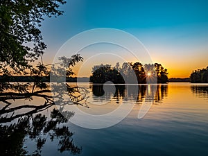 Sunset over Pymatuning Lake in Pennsylvania at the end of summer.  A fallen tree in the foreground and the sunburst coming through