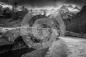 Sunset over the Pyrenees mountains, Circus of Gavarnie and the old stone bridge spanning the stream photo