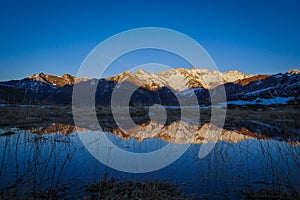 Sunset over the Pyrenees mountains with the reflection of the peaks in the water of the lake photo