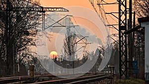 Sunset over railroad tracks, cold evening, smoke from the chimney in the sky