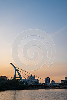 Sunset over river with modern suspension bridge in Tainan, Taiwan