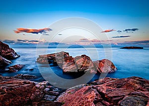 Sunset over rocks in the ocean in Canada