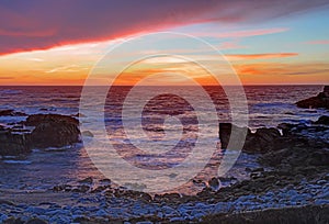 Sunset over rocks and sand at Asilomar State Beach in California