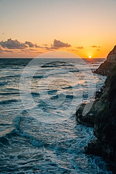 Sunset over rocky coast and the Pacific Ocean at Swami\'s Beach, in Encinitas, California