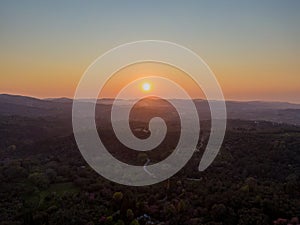 Sunset over rolling hills and valleys, casting a warm golden light across the landscape. A serene and peaceful scene