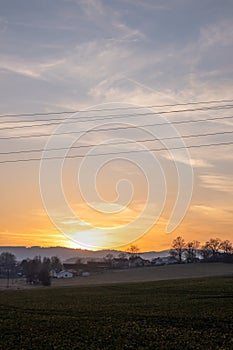 Sunset over rural village and green field photo