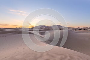 Sunset over the sand dunes in the desert. Arid landscape of the Sahara desert