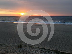 Sunset over sandy beach with calm ocean