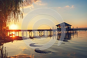 Sunset over the sea lake and old wooden pier, romantic travel destination, nature landscape