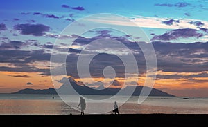 Sunset over the sea and mountains, the fisherman's silhouette ashore. Tahiti