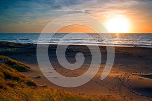 Sunset over sea and sand dunes