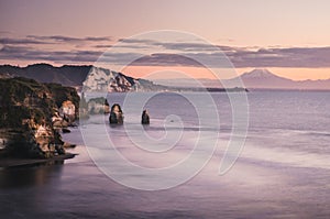 Sunset over sea shore rocks and mount Taranaki, New Zealand