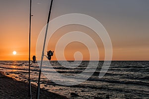 Sunset over the sea. Stones and fishing rods on the foreground