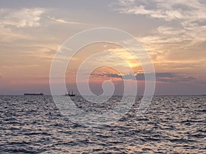 A sunset over the sea with two silhouettes of ships