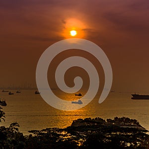 Sunset over the Singapore Strait with cargo boats and transportation ships and vessels importing and exporting goods across Asia