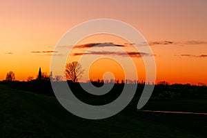 Sunset over the small town of Canalnovo, province of Rovigo. With silhouettes of trees and church.