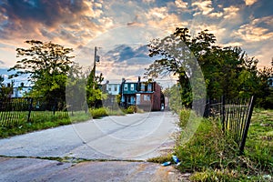 Sunset over a street and abandoned rowhouses in Baltimore, Maryland.