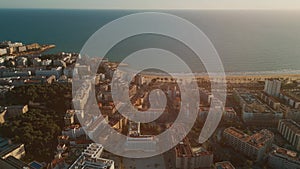 sunset over streets of Spanish touristic city Salou, Catalonia, aerial view of beach, sea and coast with palm trees