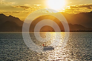 sunset over Taurus mountains, sea and Tourboat in Antalya