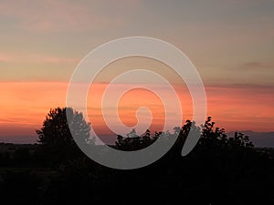 Sunset over the town, bright sky with pink, orange and purple clouds.